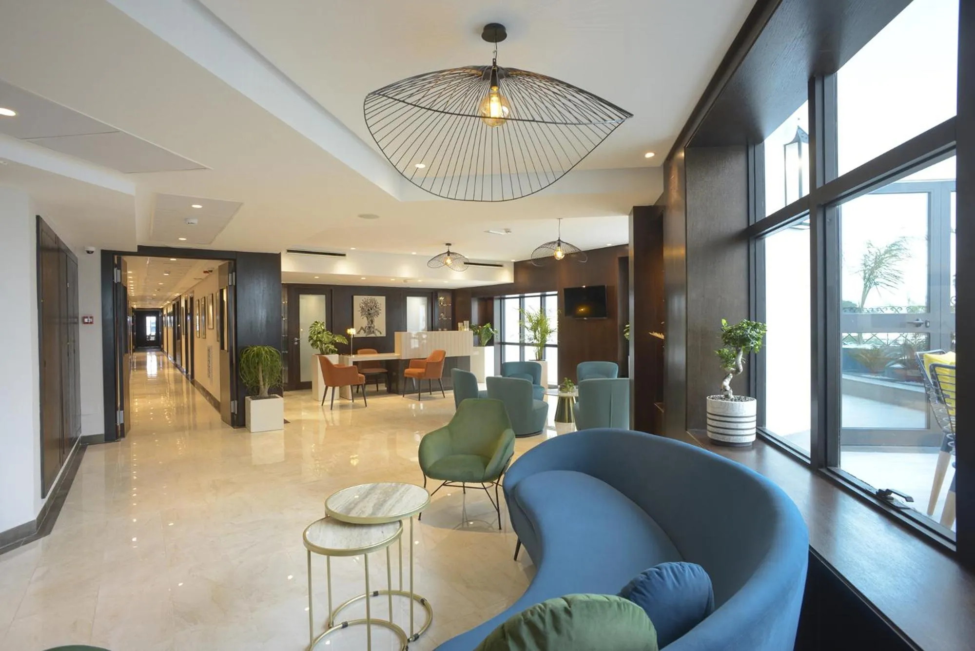 Un espace de détente intérieur avec des fauteuils et des canapés près de grandes fenêtres.