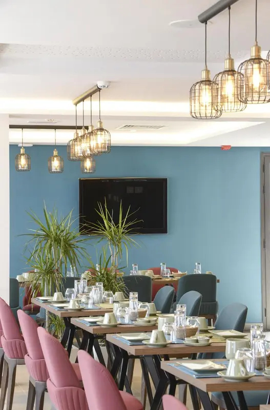 Une salle lumineuse avec des tables dressées pour le repas.