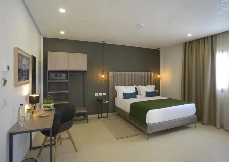 Une chambre lumineuse avec un grand lit et un espace bureau.