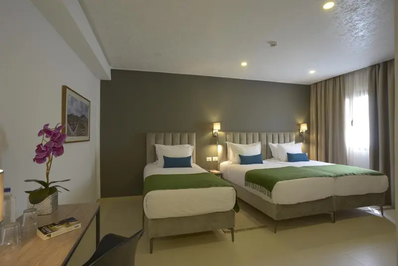 Une chambre lumineuse avec deux lits simples et une décoration sobre.