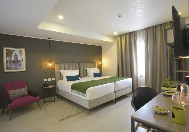 Une chambre lumineuse avec un grand lit et un coin repas.