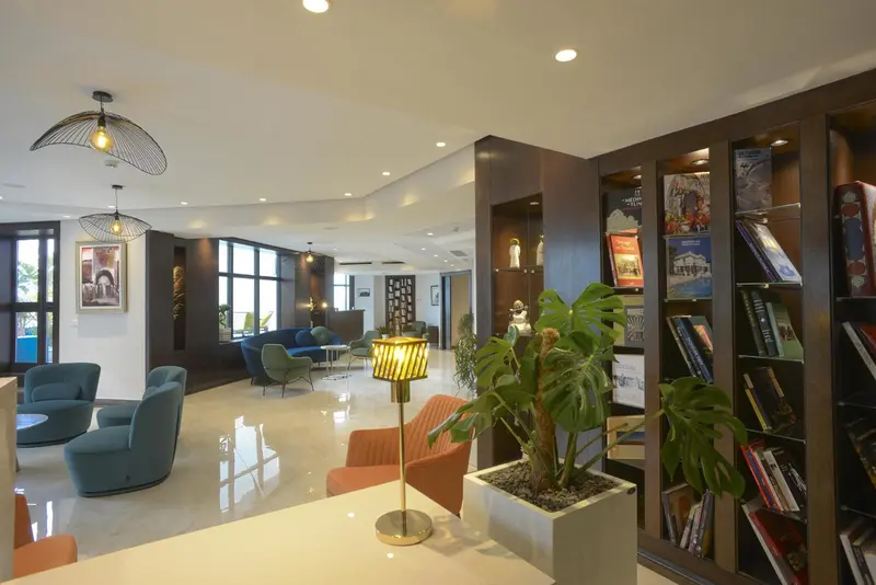 Espace de détente lumineux avec des fauteuils et une bibliothèque.