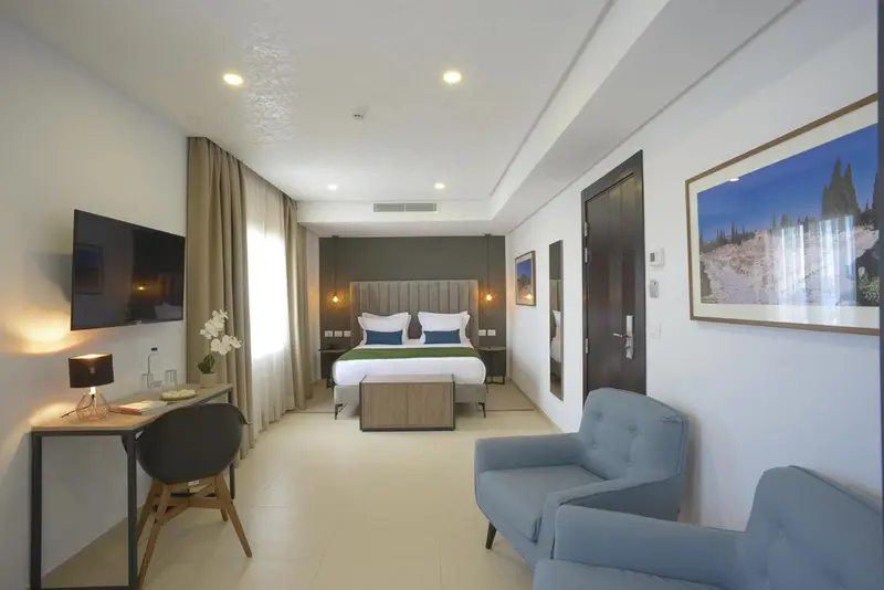 Une chambre lumineuse avec un lit double et un coin salon.