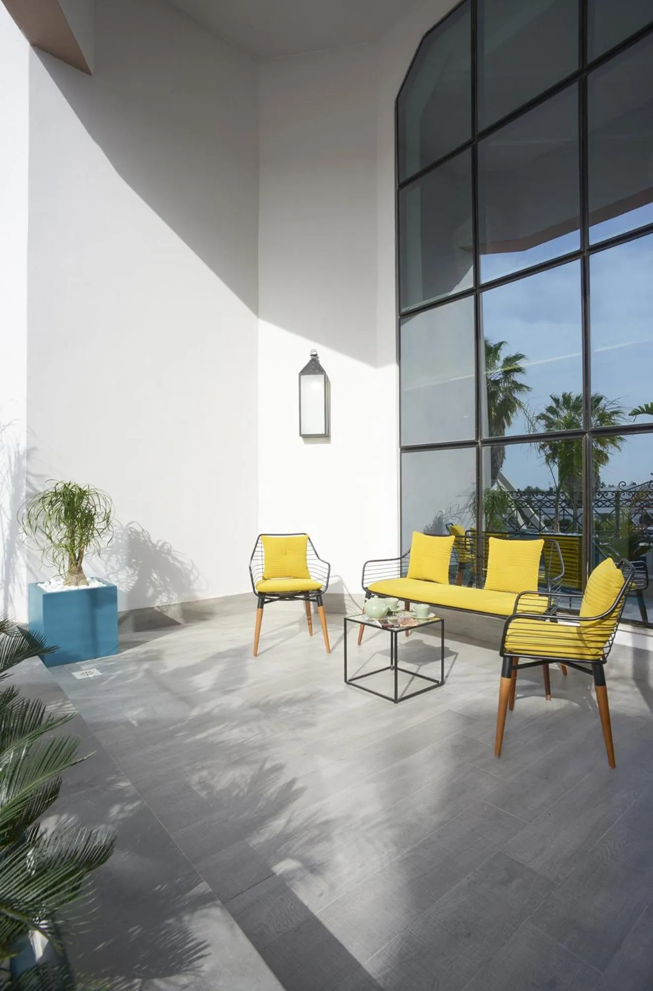 Espace de détente intérieur avec mobilier jaune et grande baie vitrée.