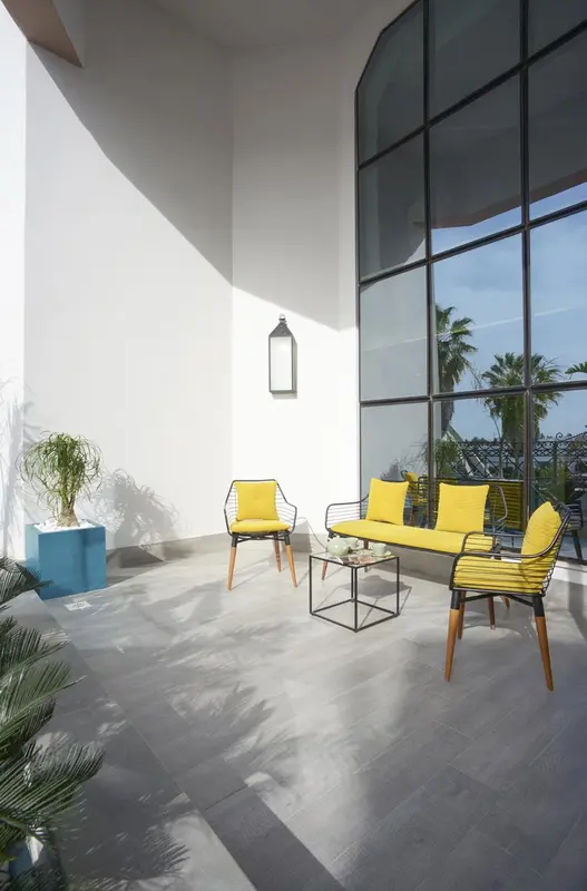 Espace de détente intérieur avec mobilier jaune et grande baie vitrée.