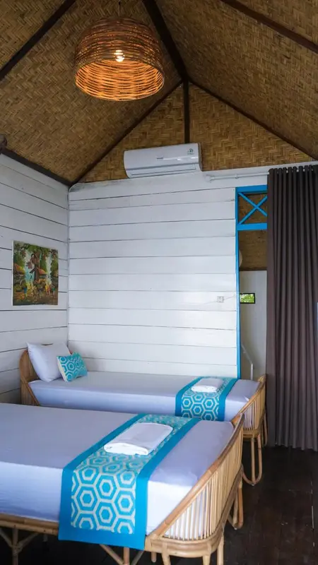Une chambre lumineuse avec deux lits simples et un décor tropical.