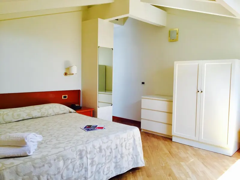 Une chambre lumineuse avec un lit et un meuble de rangement.