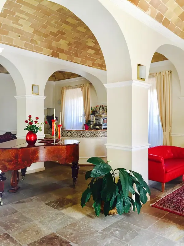 Un espace intérieur lumineux avec des arches et un piano à queue.