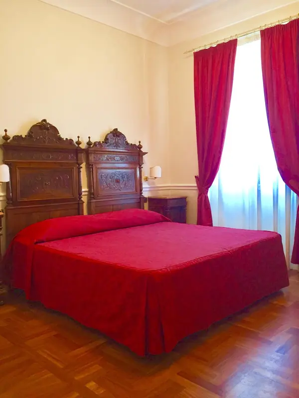 Une chambre à coucher avec un grand lit recouvert d'une couverture rouge et des rideaux assortis.