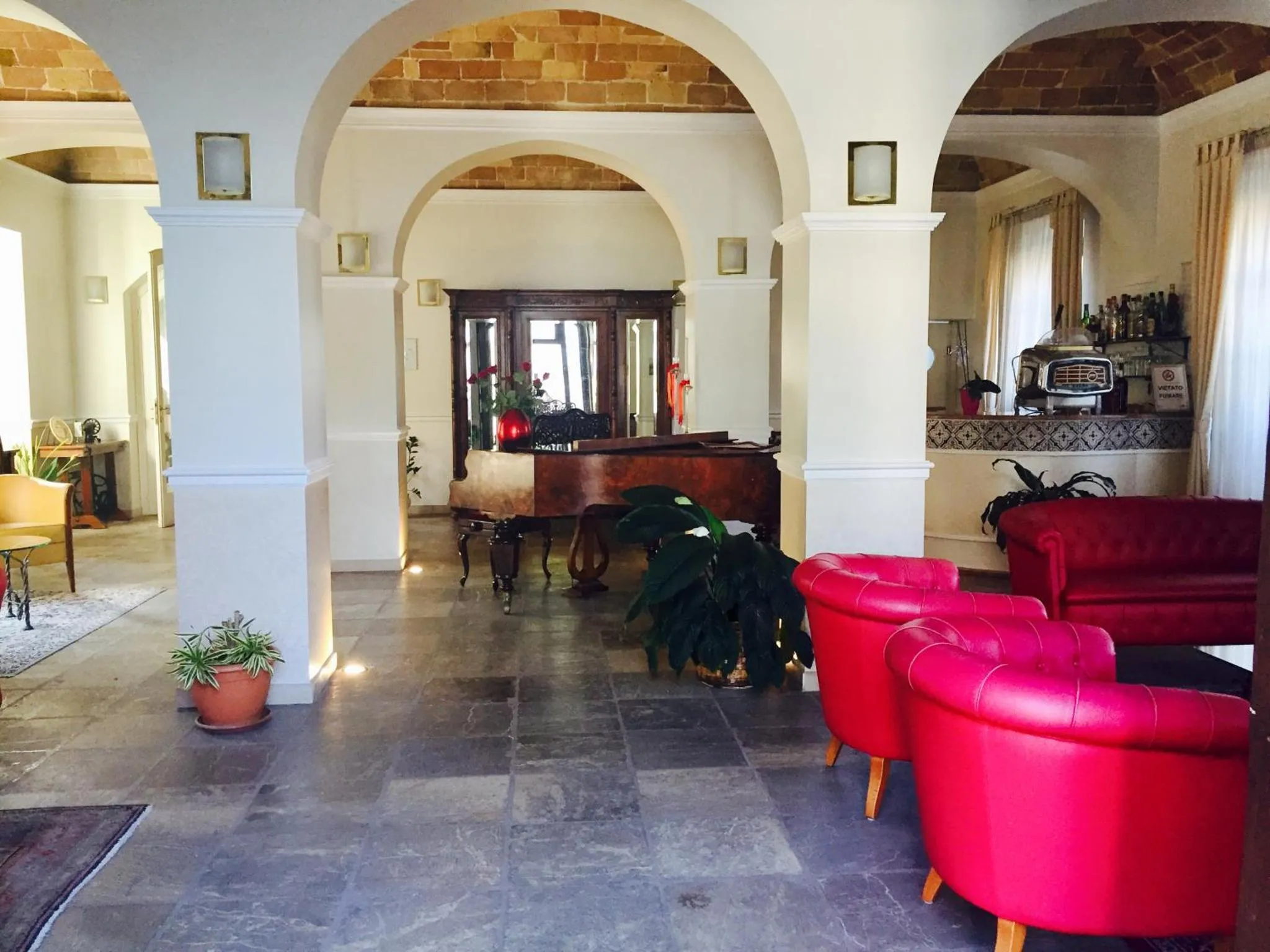Espace intérieur lumineux avec des arches et des fauteuils colorés.