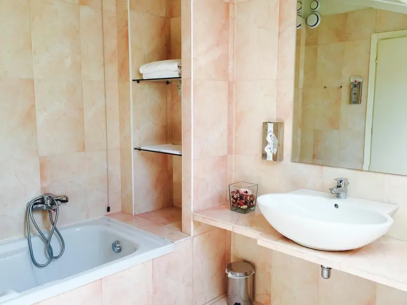 Une salle de bain claire avec baignoire et vasque blanche.