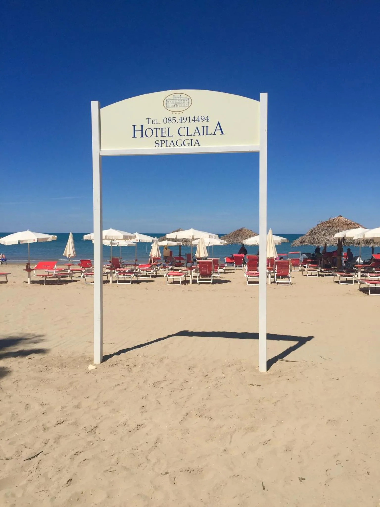 Plage de sable avec transats et parasols sous un ciel bleu.