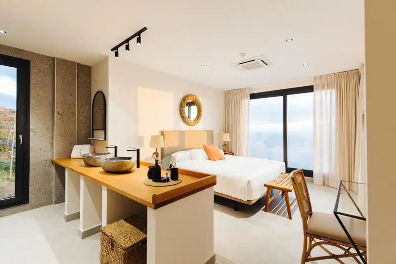 Une chambre lumineuse avec un grand lit et un coin toilette.
