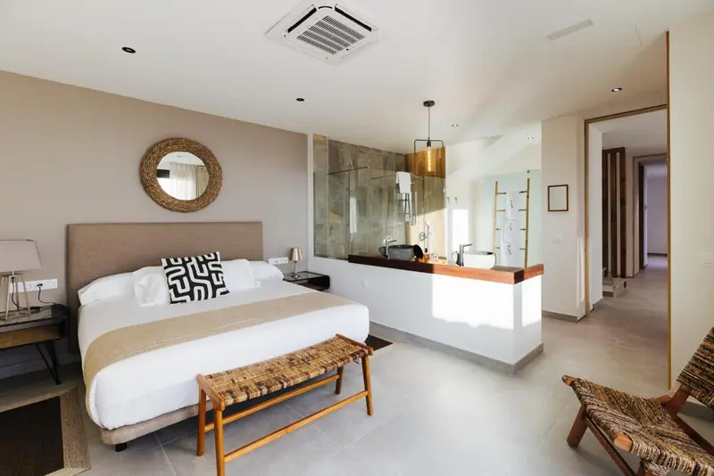 Une chambre lumineuse avec un grand lit et un espace salle de bain ouvert.