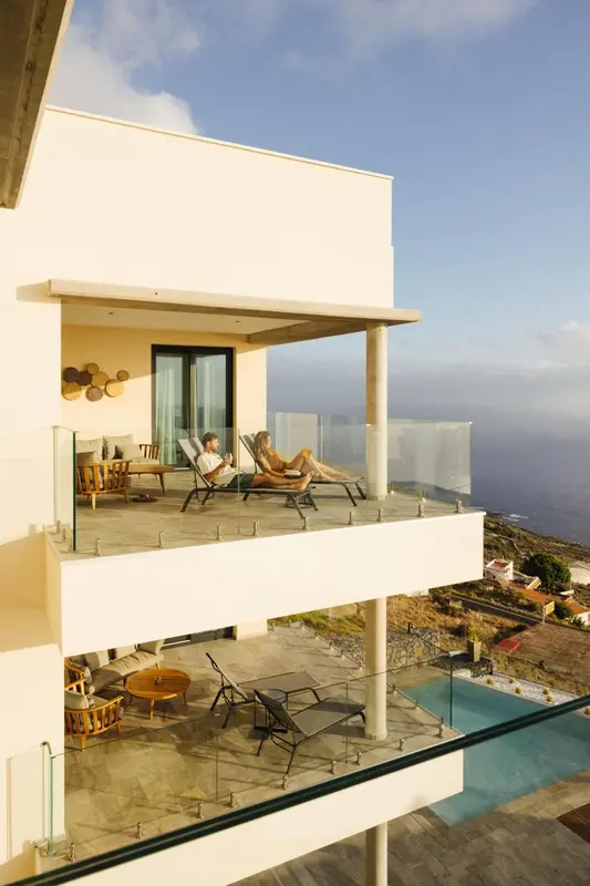 Deux personnes se détendent sur une terrasse avec vue sur la mer.