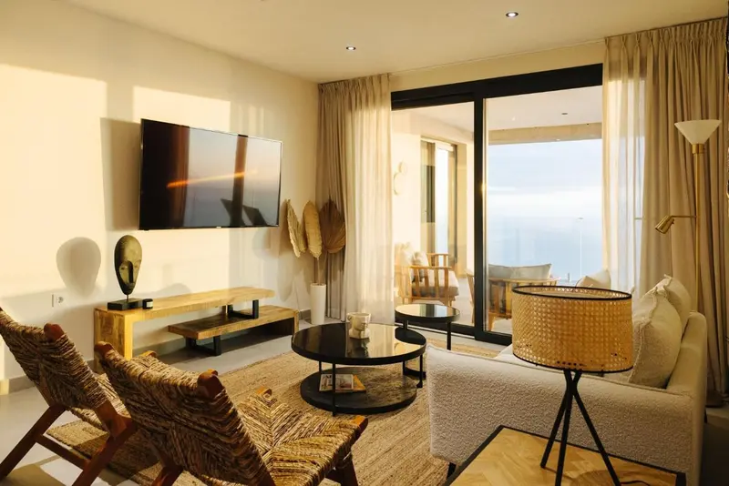 Un salon lumineux avec canapés et télévision face à une baie vitrée.