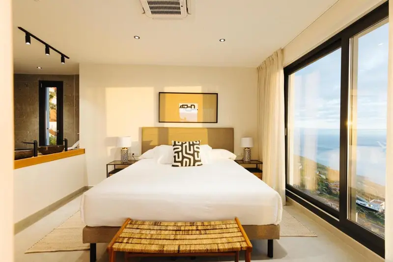 Une chambre lumineuse avec un grand lit et une vue sur la mer.