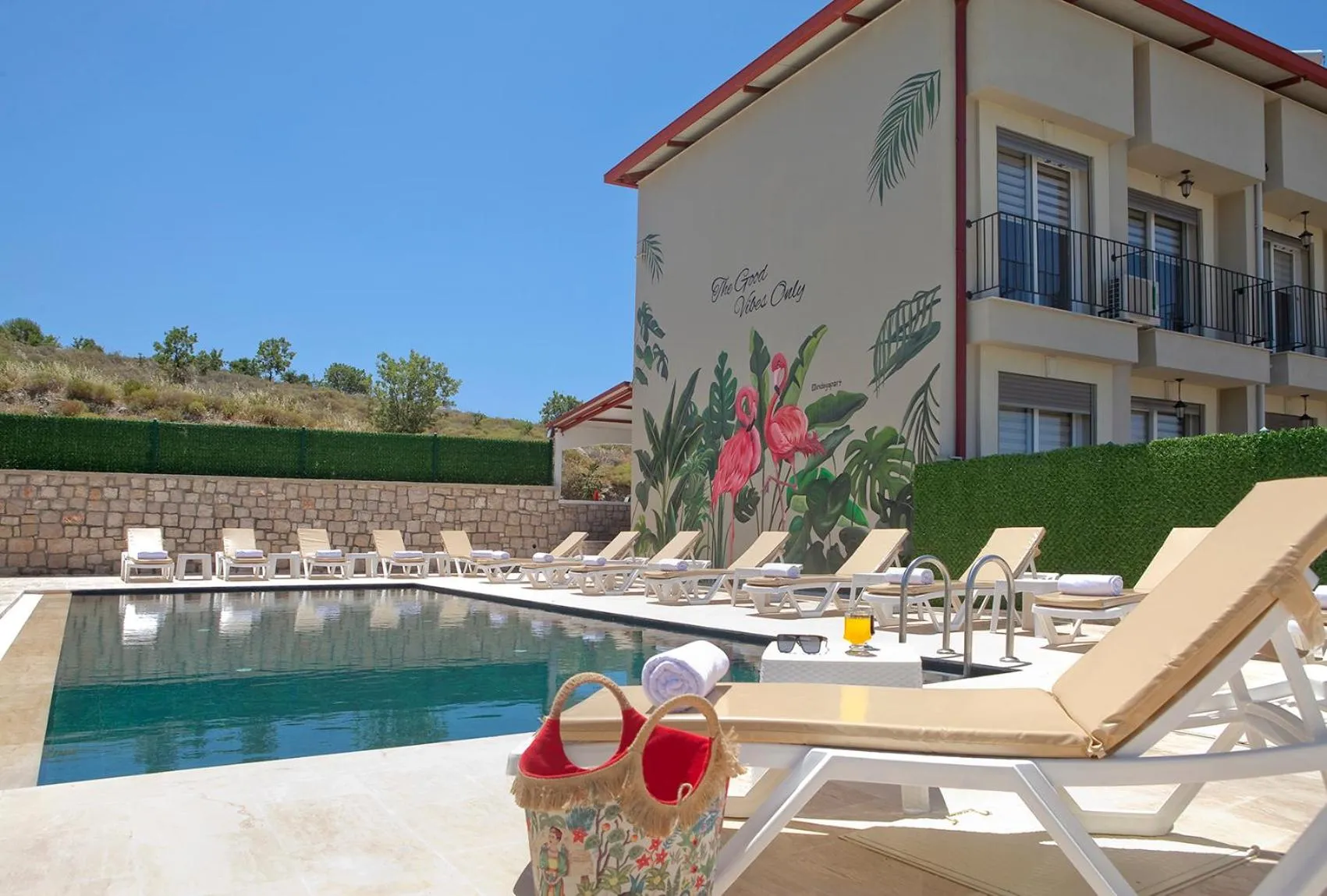 Transats alignés au bord d'une piscine ensoleillée devant un bâtiment.