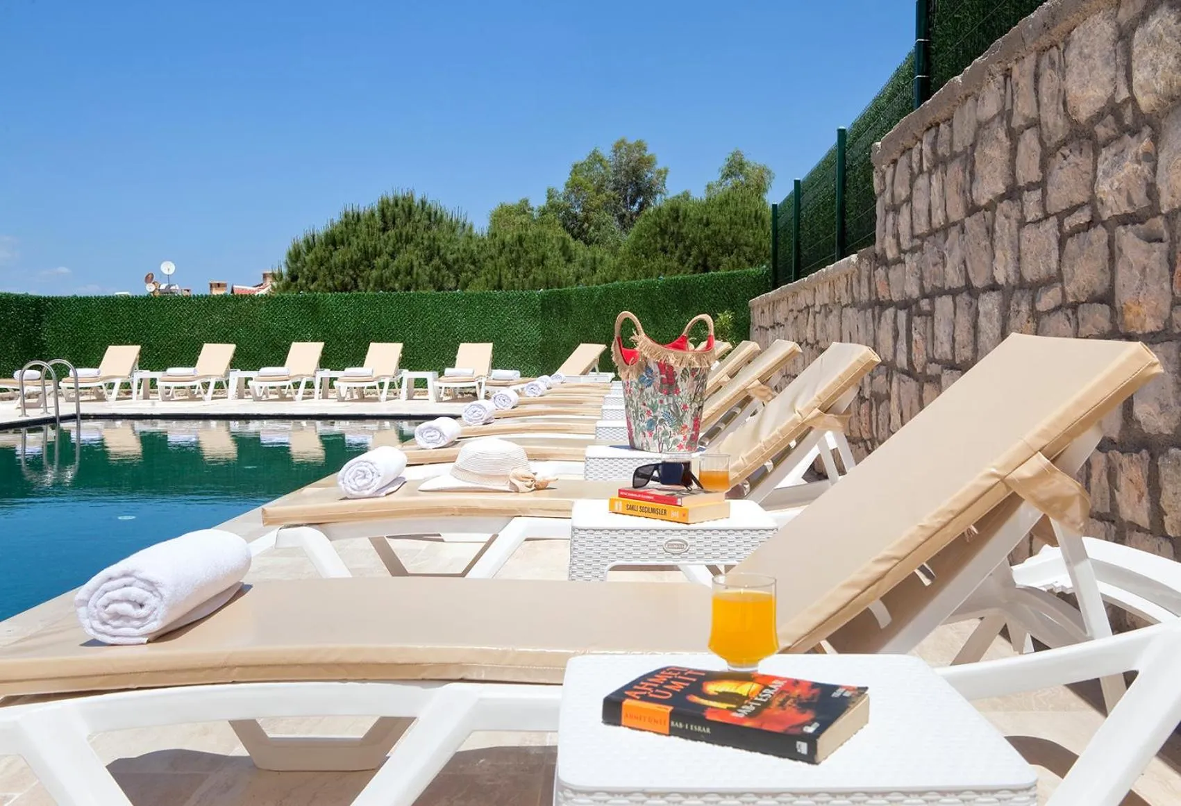 Transats blancs alignés au bord d'une piscine turquoise sous le soleil.