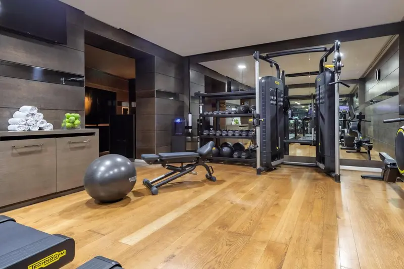 Une salle de sport lumineuse avec des équipements de musculation et des miroirs.