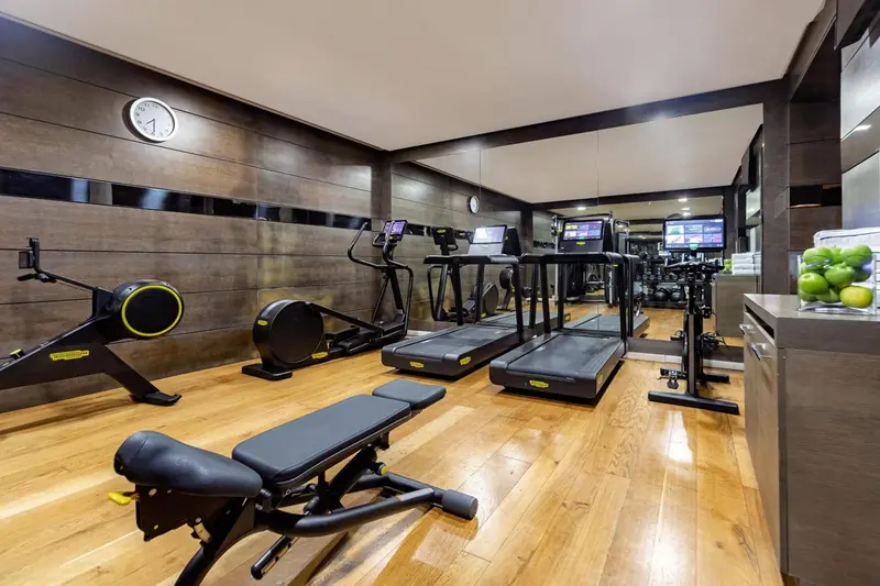 Une salle de sport lumineuse avec des équipements de fitness et un sol en bois.