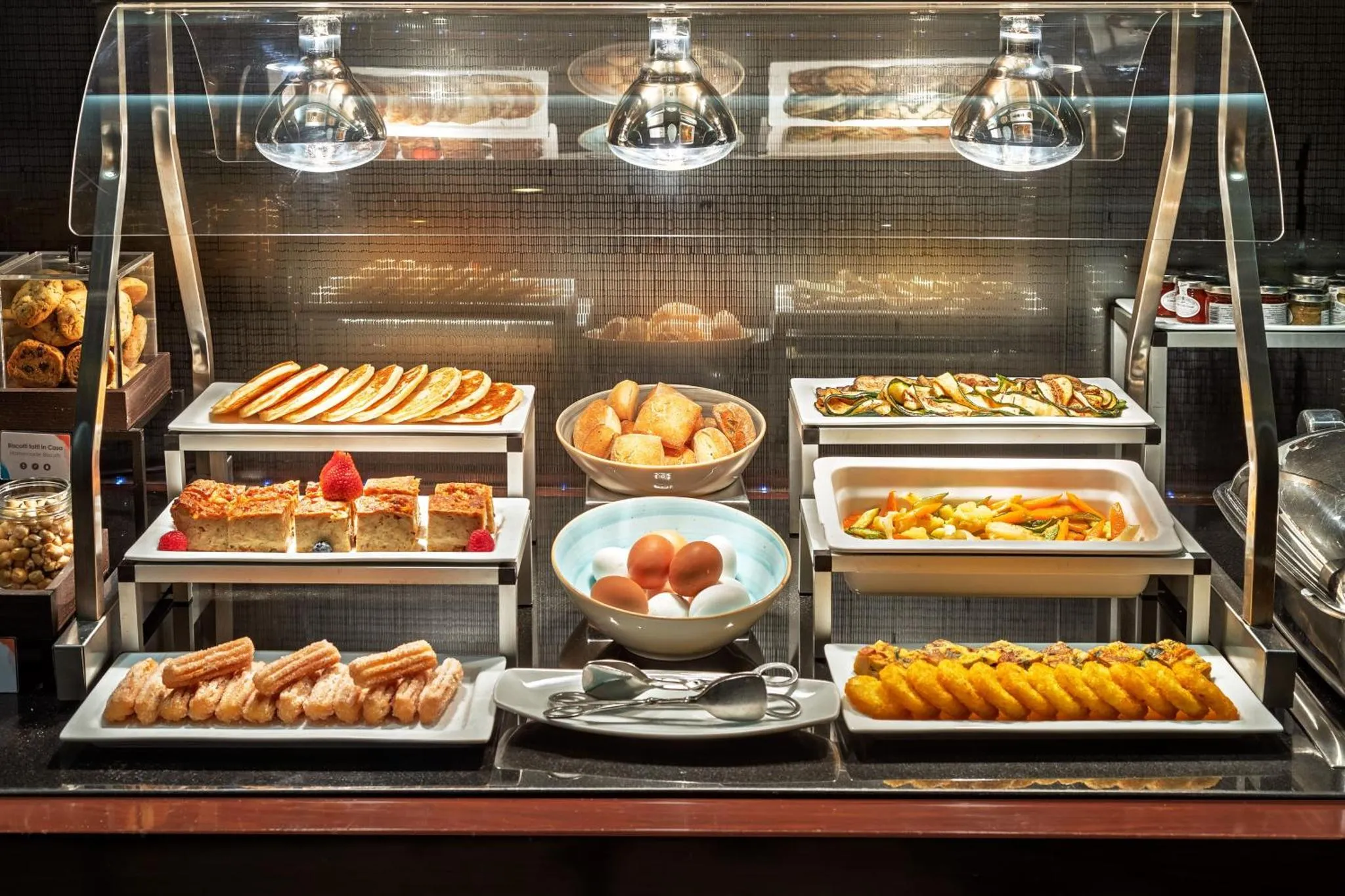 Présentation de viennoiseries, pâtisseries et plats chauds sur un buffet.