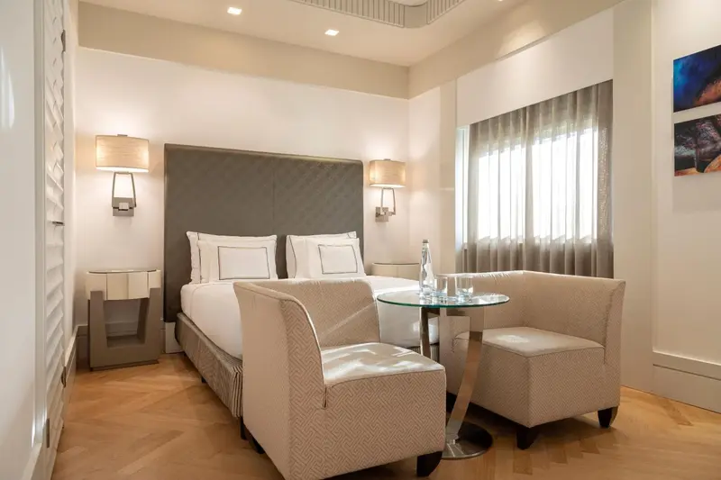 Une chambre lumineuse avec un lit double et un coin salon.