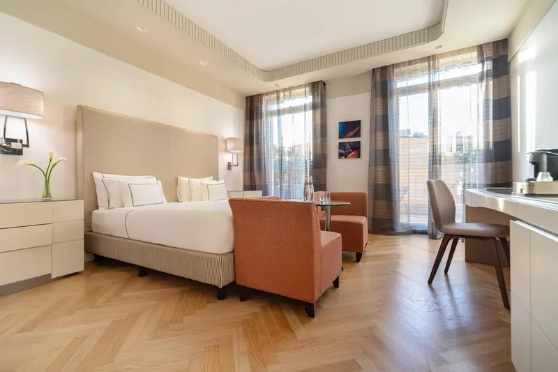 Chambre lumineuse avec un grand lit et un coin salon.
