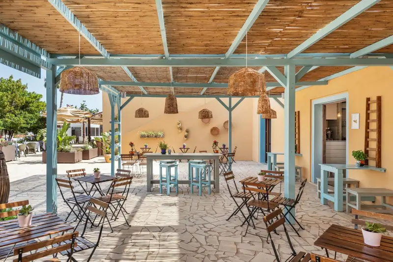 Terrasse ombragée avec tables et chaises en fer forgé.