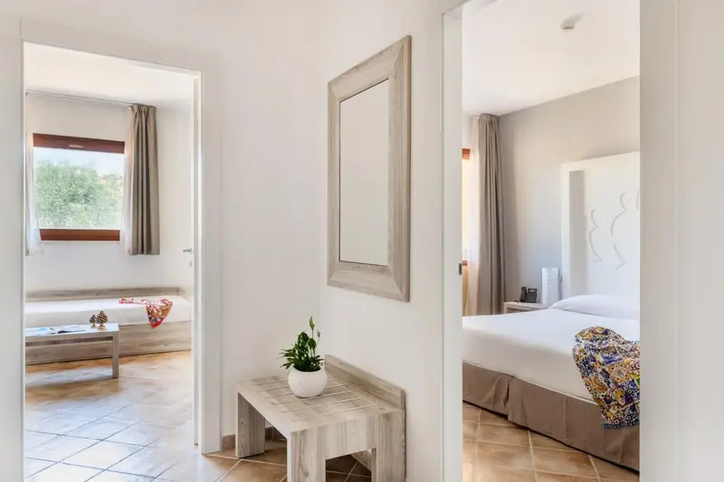 Intérieur clair avec un lit et un espace salon ouvert.