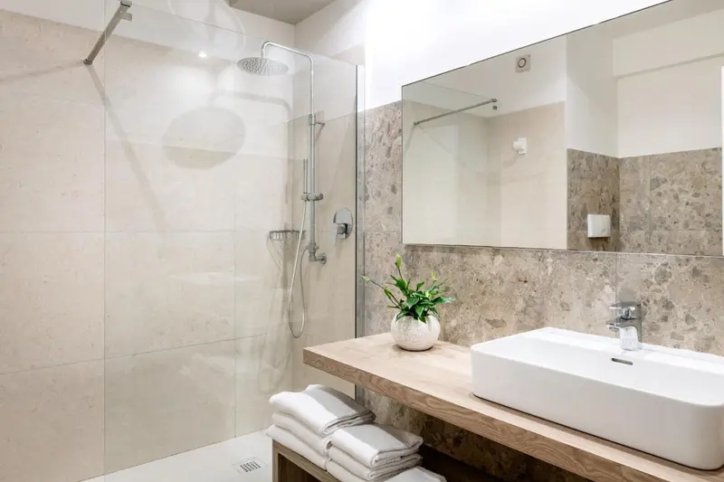 Une douche à l'italienne moderne avec des carreaux beiges et un lavabo blanc.