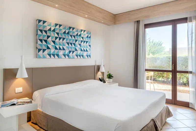Une chambre lumineuse avec un grand lit et un tableau décoratif.