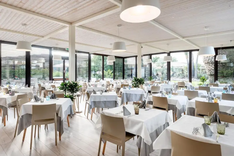 Une salle lumineuse avec des tables dressées pour un repas.