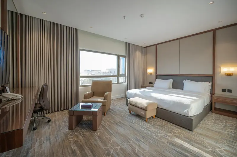 Une chambre d'hôtel lumineuse avec un lit double et un fauteuil.