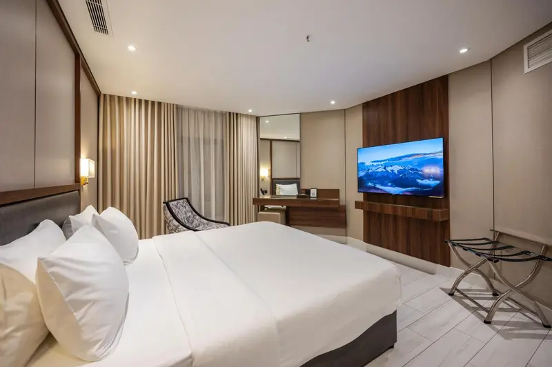 Une chambre d'hôtel lumineuse avec un grand lit et un téléviseur mural.