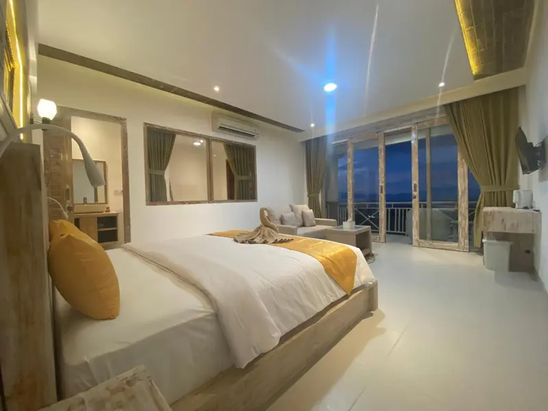 Chambre lumineuse avec un grand lit et un accès à une terrasse.