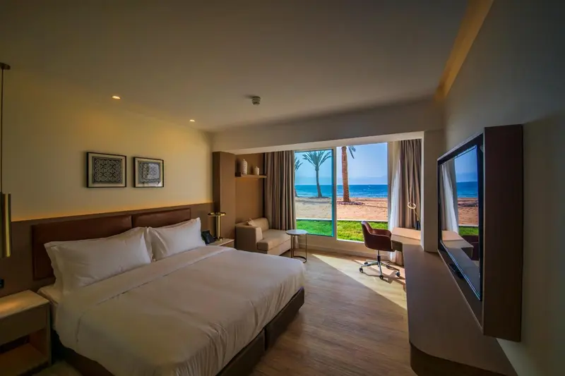 Chambre lumineuse avec un grand lit et une vue sur la mer.