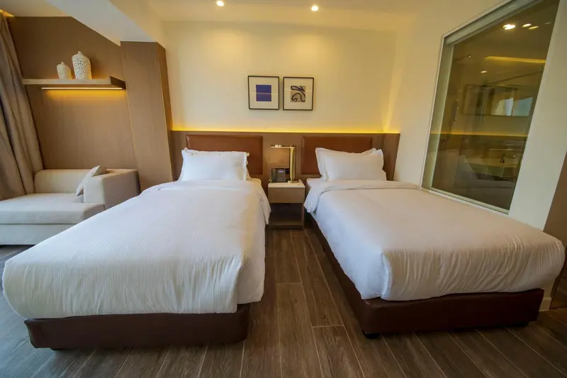 Une chambre lumineuse avec deux lits simples et un coin salon.