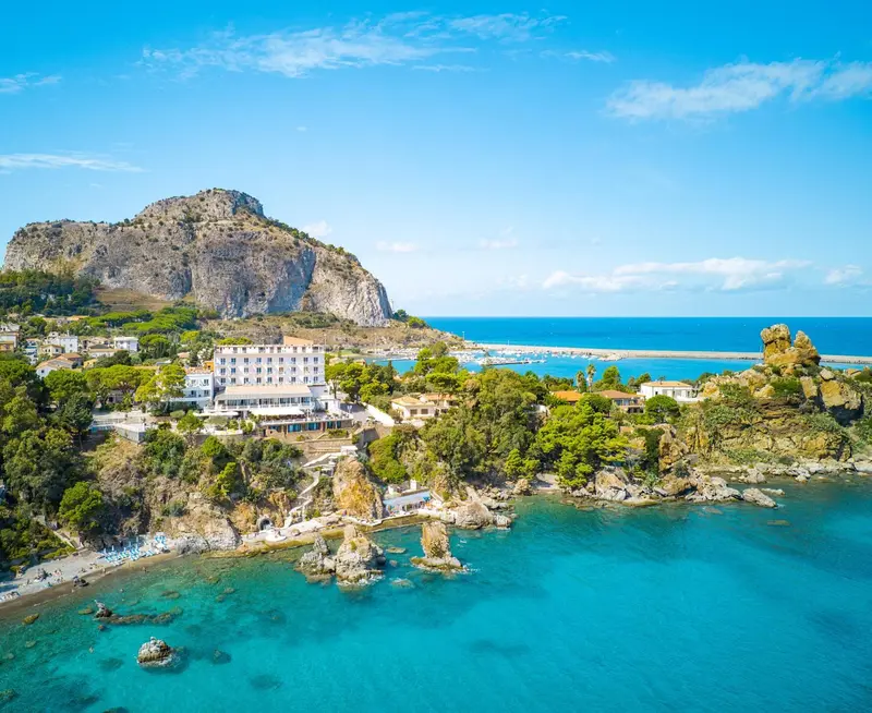 Vue aérienne d'un établissement côtier avec une plage et des formations rocheuses.