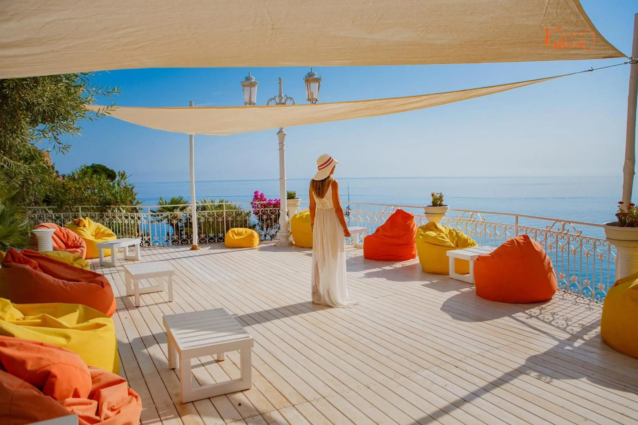 Une personne se tient sur une terrasse en bois avec vue sur la mer.