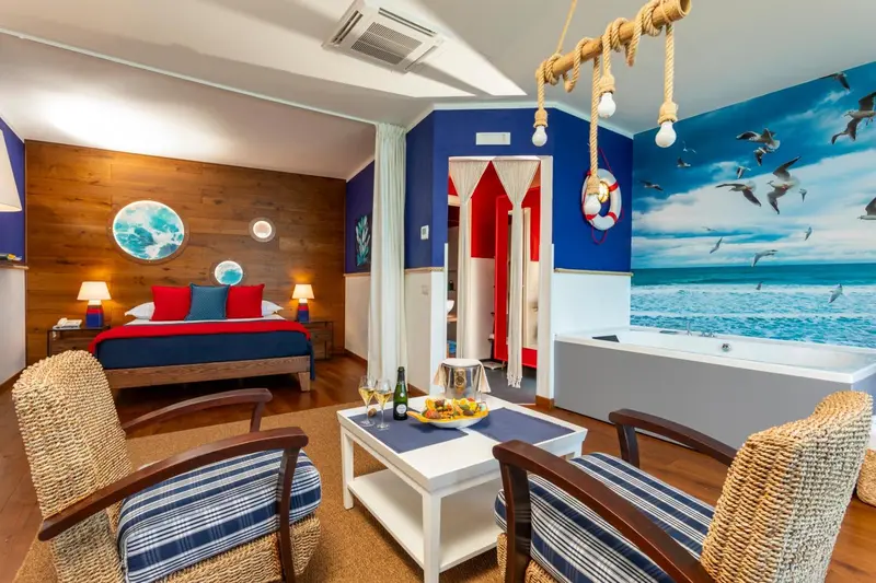Chambre décorée sur le thème de la mer avec un lit rouge et bleu et un coin salon.