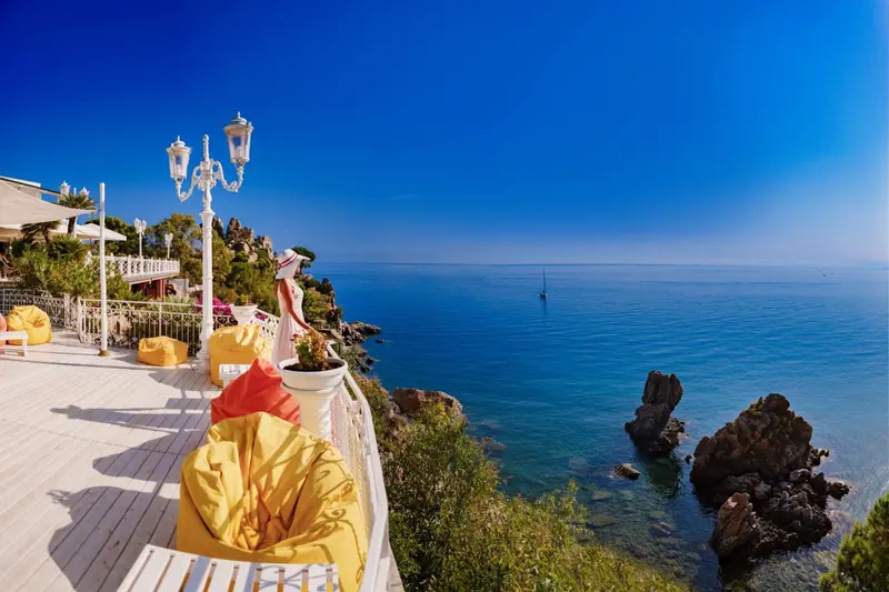 Terrasse ensoleillée avec mobilier d'extérieur dominant la mer.