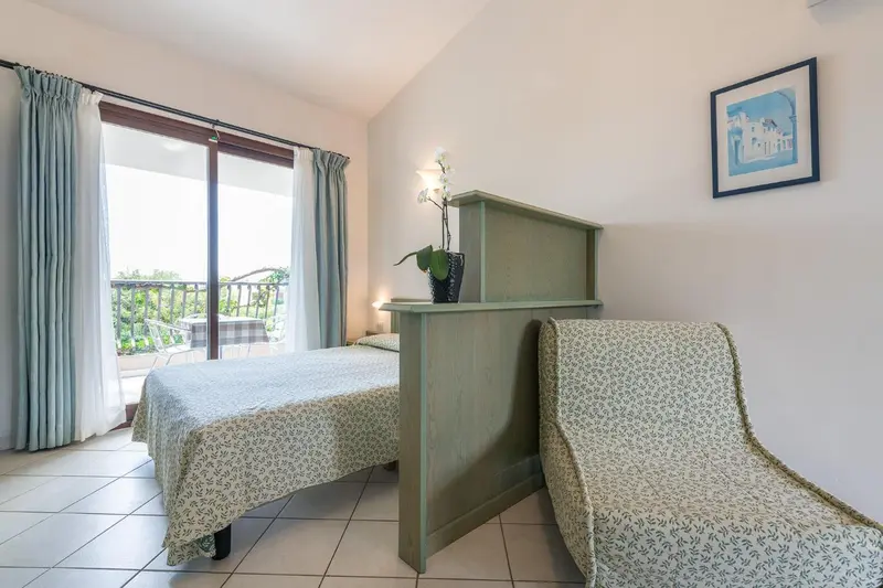 Une chambre lumineuse avec deux lits et un accès à un balcon.