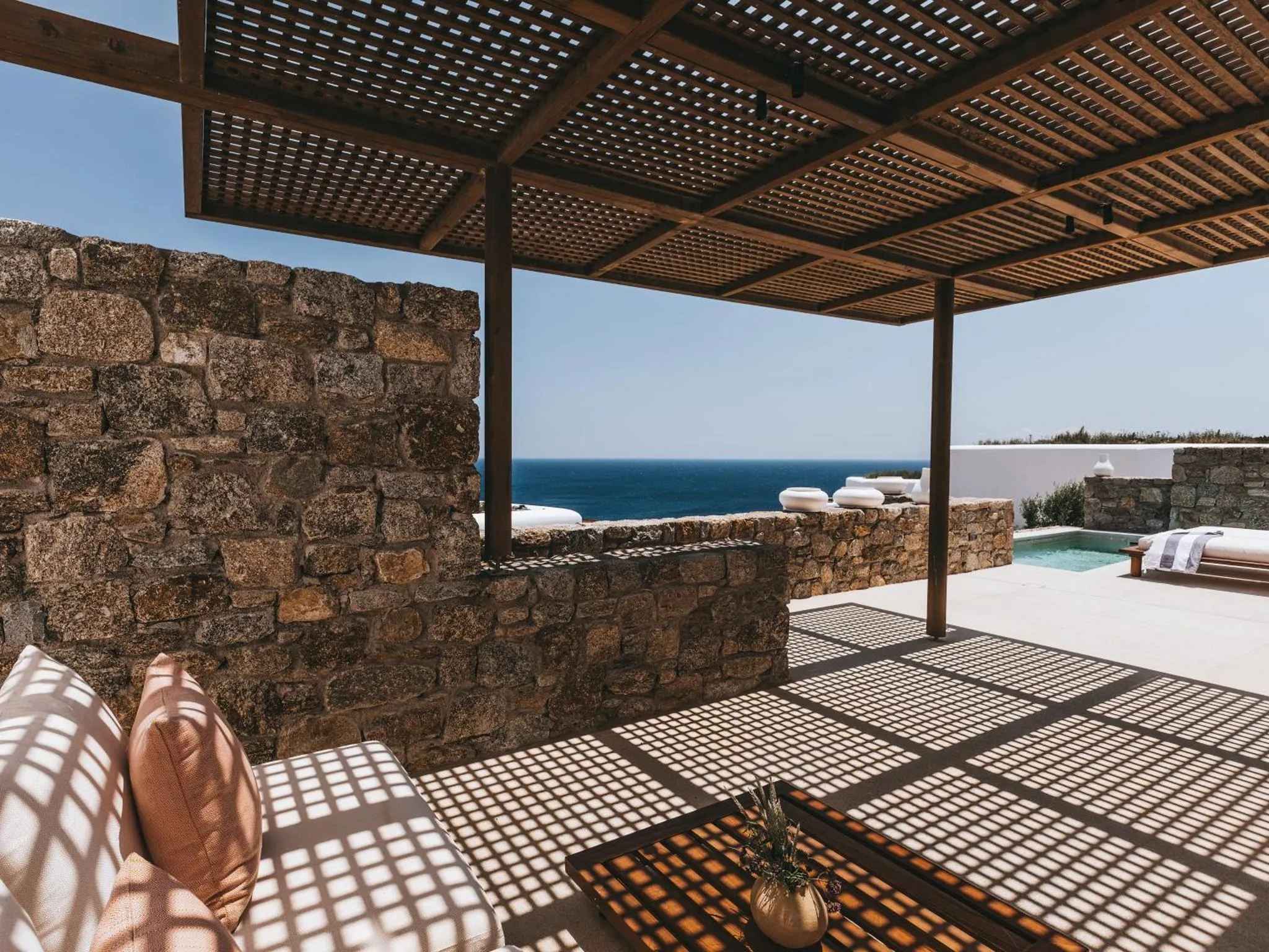 Terrasse ombragée avec vue sur la mer et une piscine.