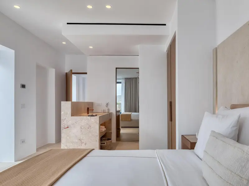 Chambre lumineuse avec un lit confortable et une salle de bain ouverte.