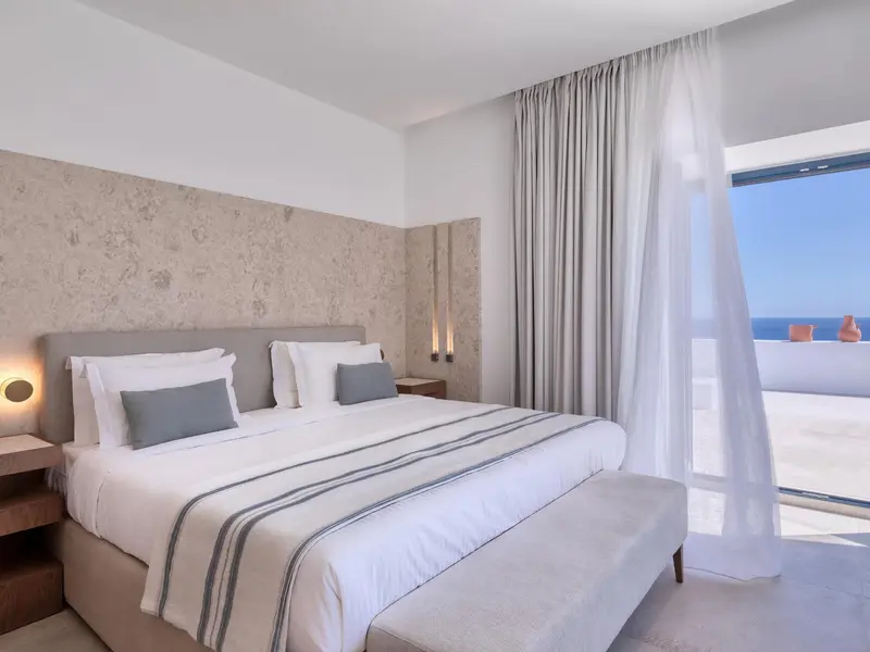 Une chambre lumineuse avec un grand lit et vue sur la mer.