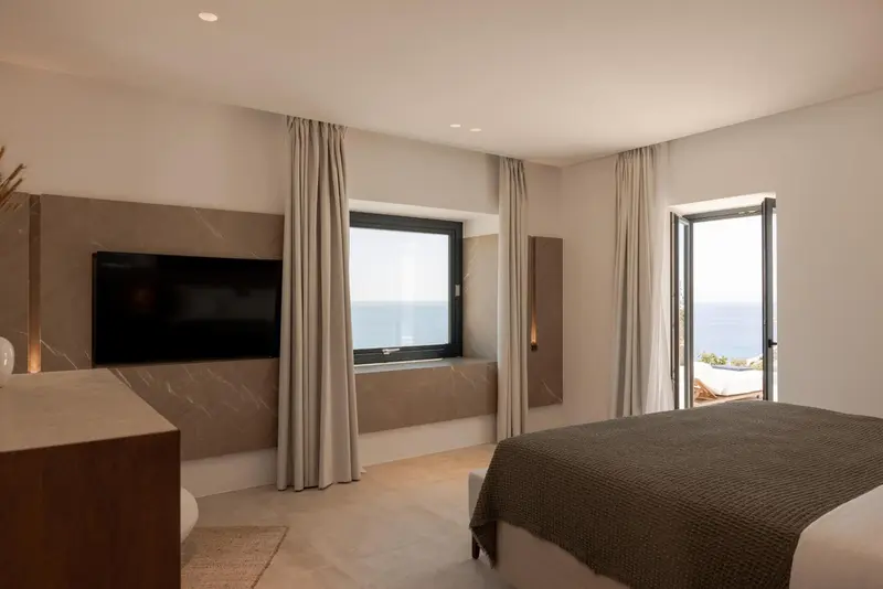 Une chambre lumineuse avec un grand lit et vue sur la mer.