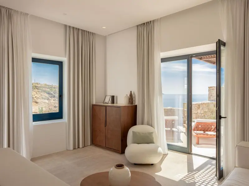 Une chambre lumineuse s'ouvre sur une terrasse avec vue sur la mer.