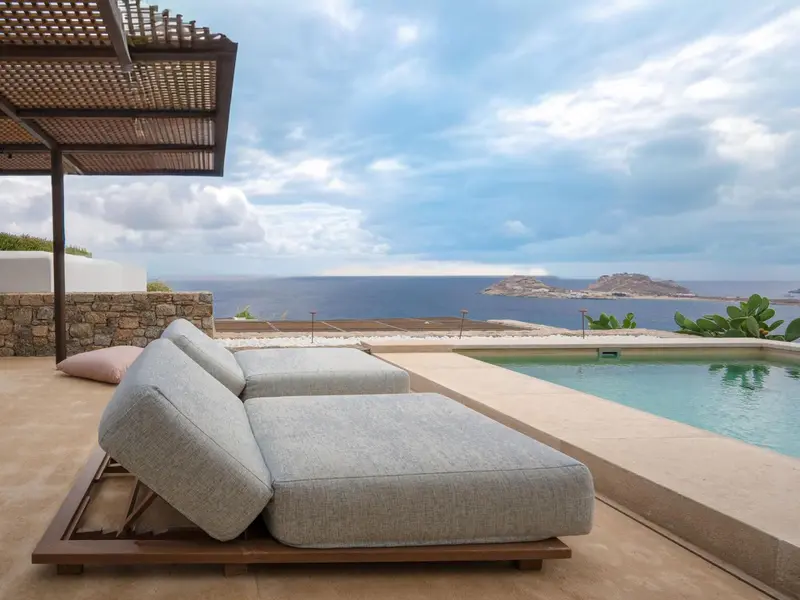 Transats et piscine au bord d'une terrasse ensoleillée avec vue sur la mer.
