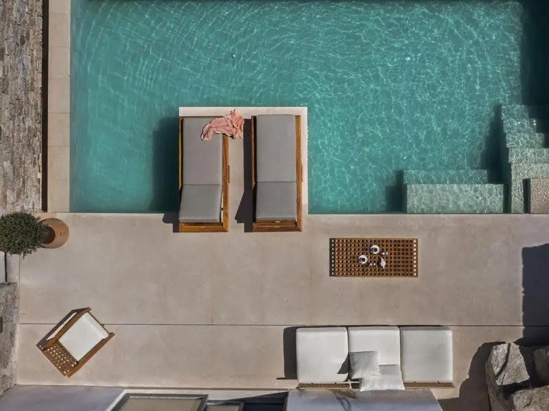 Transats et table basse au bord d'une piscine rectangulaire.
